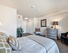 A bedroom with a bed, a chair, a lamp, and a potted plant. The bed is covered with a gray comforter. AI generated content